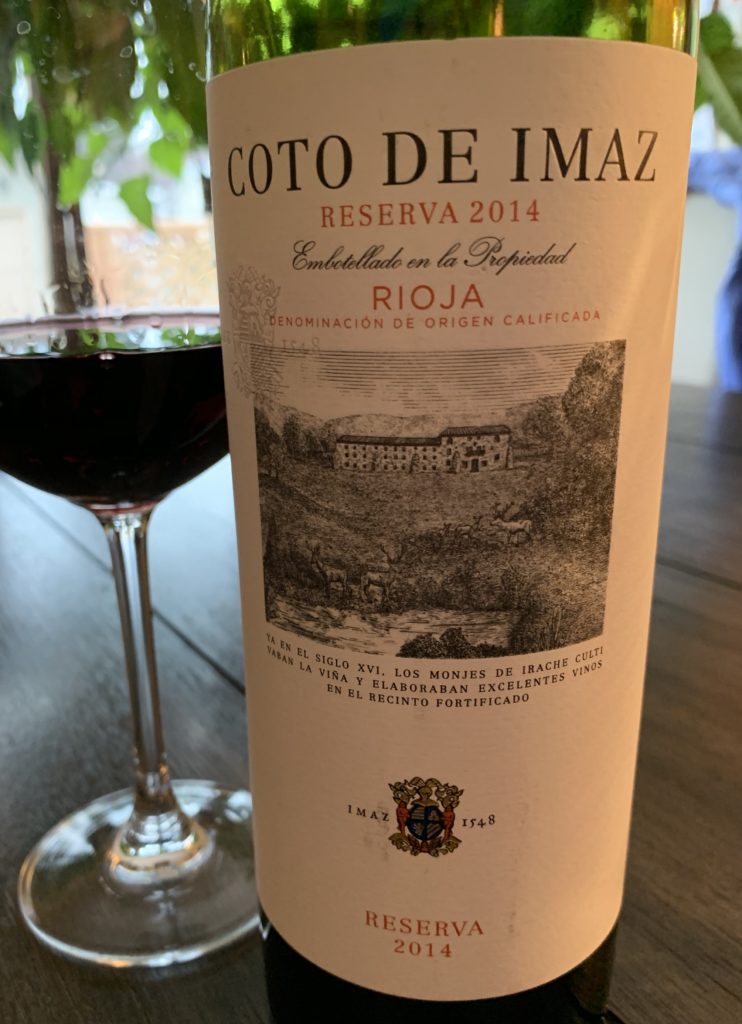 a glass of red wine sitting beside a bottle of Coto de Imaz Reserva Rioja