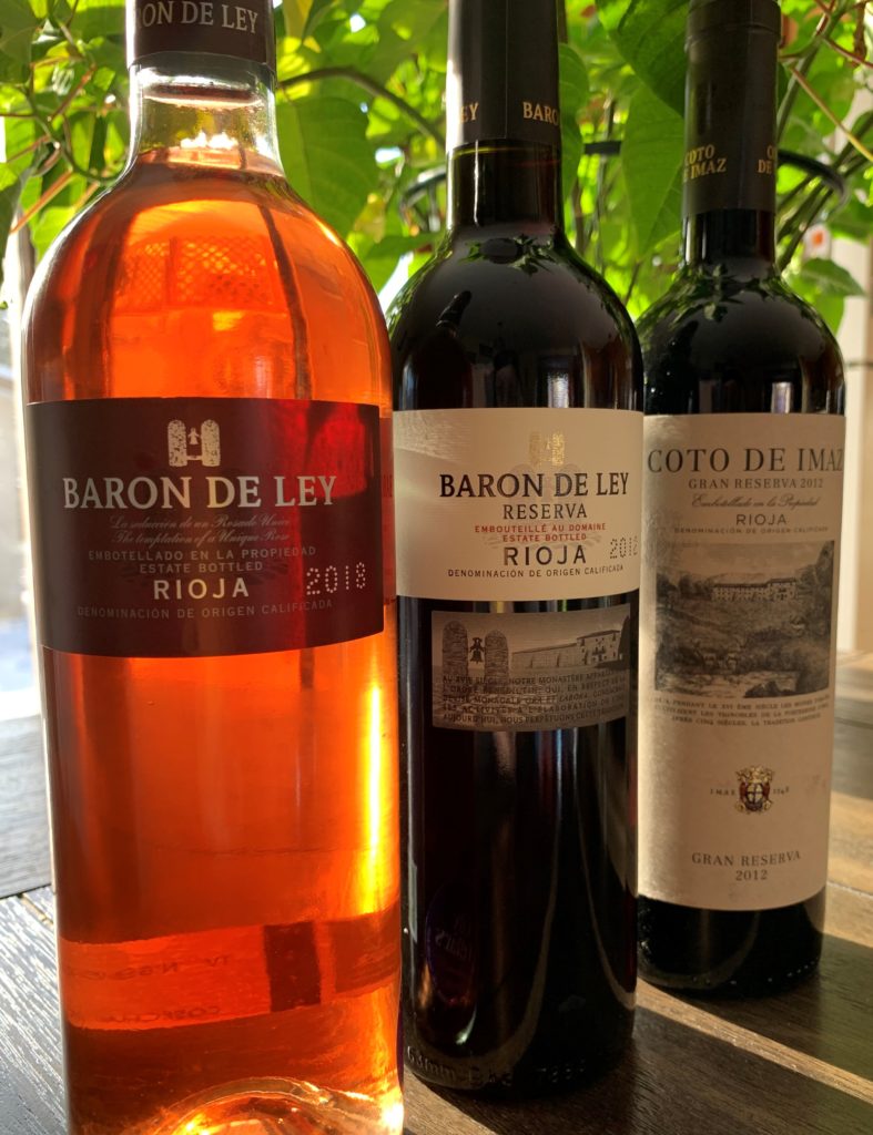 three bottles of Rioja wine from Baron de Ley with a green plant behind them